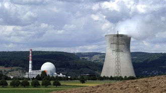 A nuclear reactor, associated buildings and a cooling tower of the Leibstadt Nuclear Power Plant are shown beneath a cloudy sky