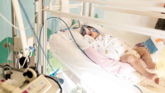 A baby lying in a hospital bed, eyes close, receiving treatment for a lung infection