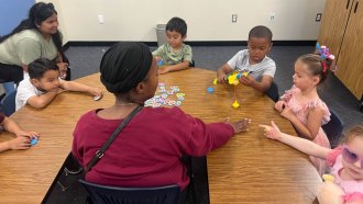 Caregivers help children practice sharing through federally-funded program.
