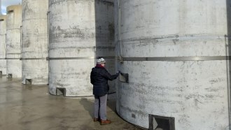 A person stands next to a row of large concrete cylinders used for storing nuclear waste.