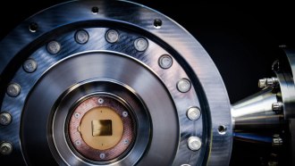 A golden-colored quantum computing chip sits at the center of a metallic, circular vacuum chamber.