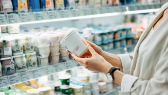 Probiotic bacteria like those in yogurt don't protect against pathogens equally well. In this picture a woman's hands are visible holding a container of yogurt in the dairy aisle of a grocery store.