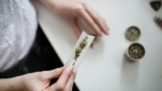 A person holding marijuana on a white paper.